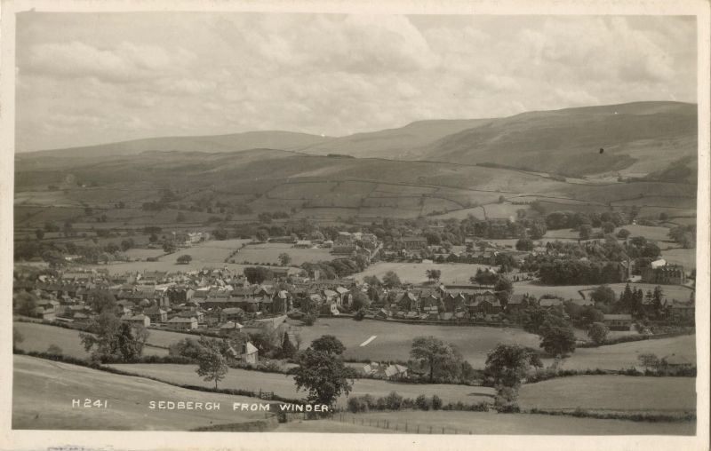 Black & white photo of a small town in a valley of fields